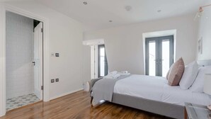 Een slaapkamer met een bed, een glazen tafel en een deur naar een andere kamer.