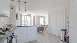 Een moderne keuken met een centraal eiland, witte kasten en hanglampen.