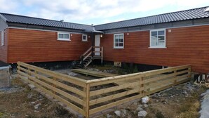 A two-story wooden house with a wooden deck and a staircase leading to the upper floor. - IceCap Apartments (Ilulissat)