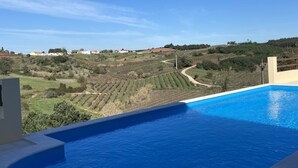 A swimming pool with a view of a vineyard and distant buildings.
