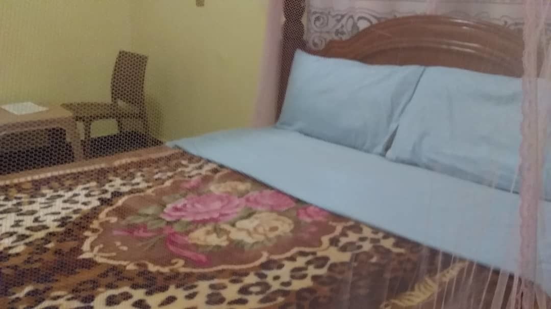 Una cama con una colcha de estampado floral y un cojín azul claro.