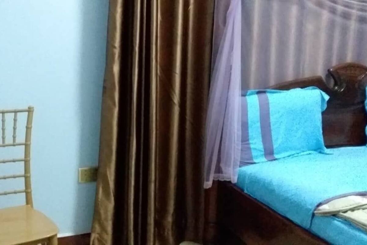 Una habitación con cama, una silla y una cortina.