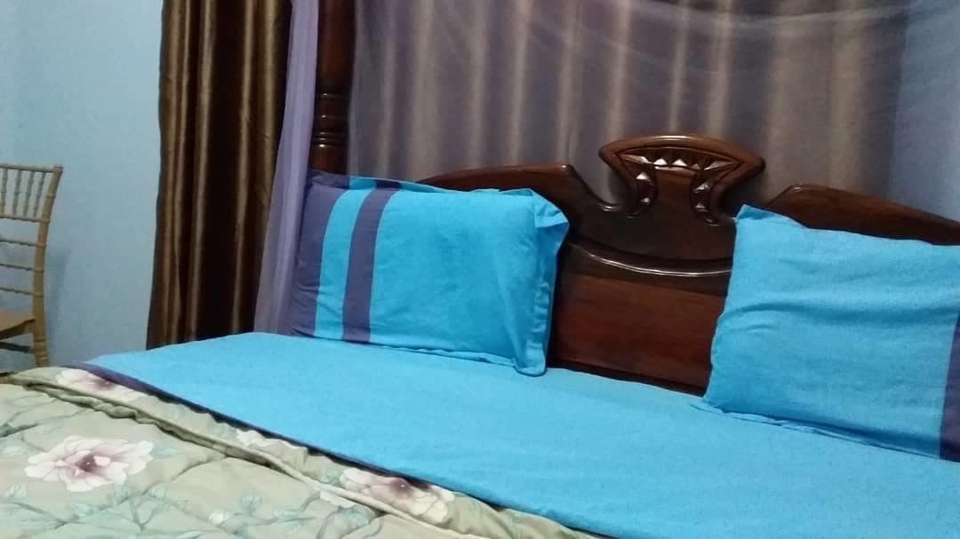 A bed with a floral-patterned bedspread and two blue pillows.