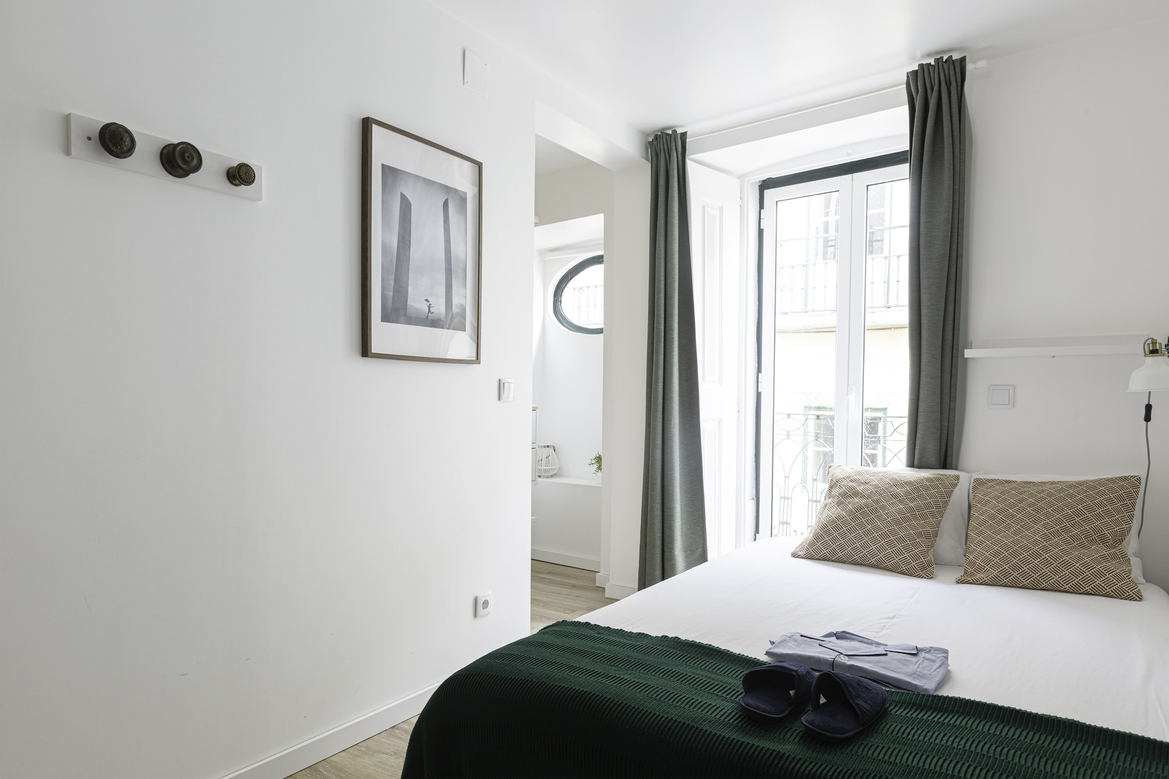 A hotel room with a bed, a framed picture on the wall, and a window with curtains.