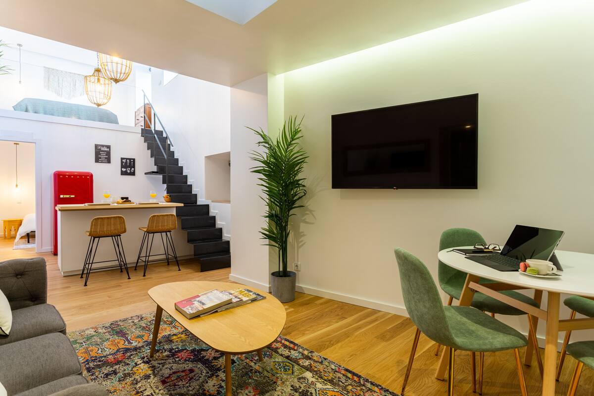 A modern living space with a staircase, a dining area, and a kitchen area.