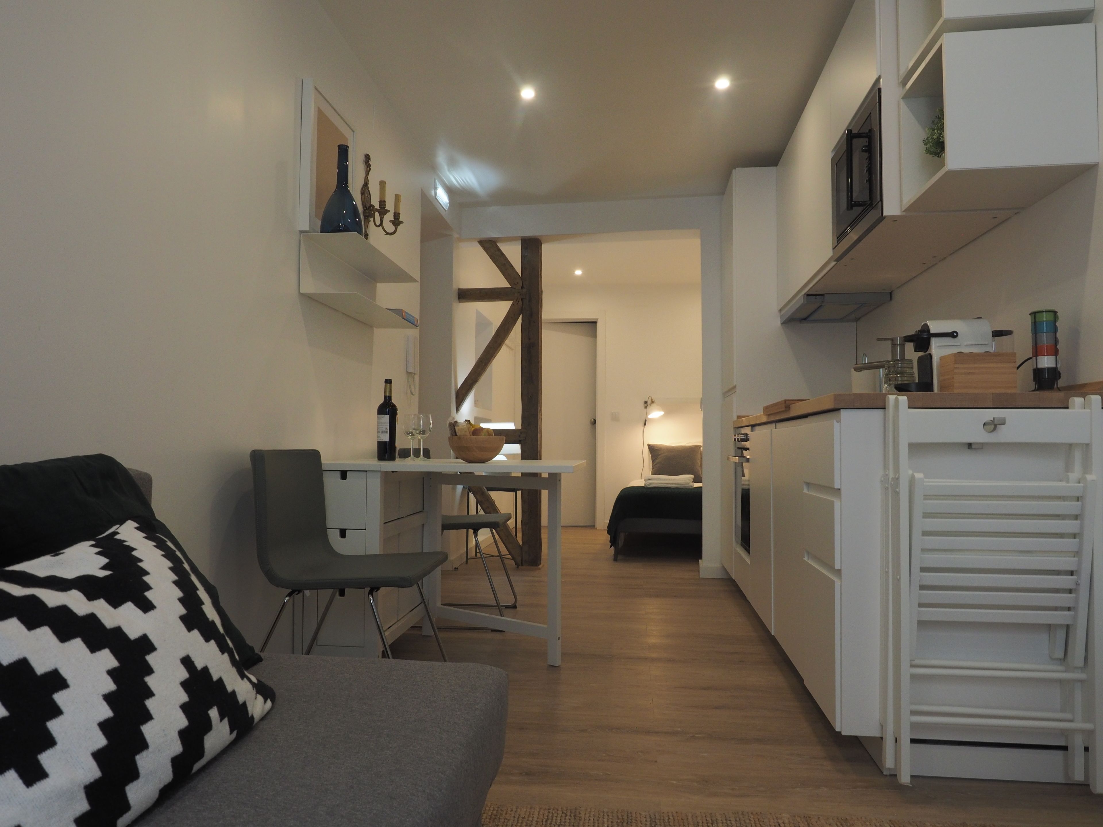 Ein kompakter Wohnraum mit Küchenzeile, Essbereich und einer Sitzecke mit Sofa und Sessel.