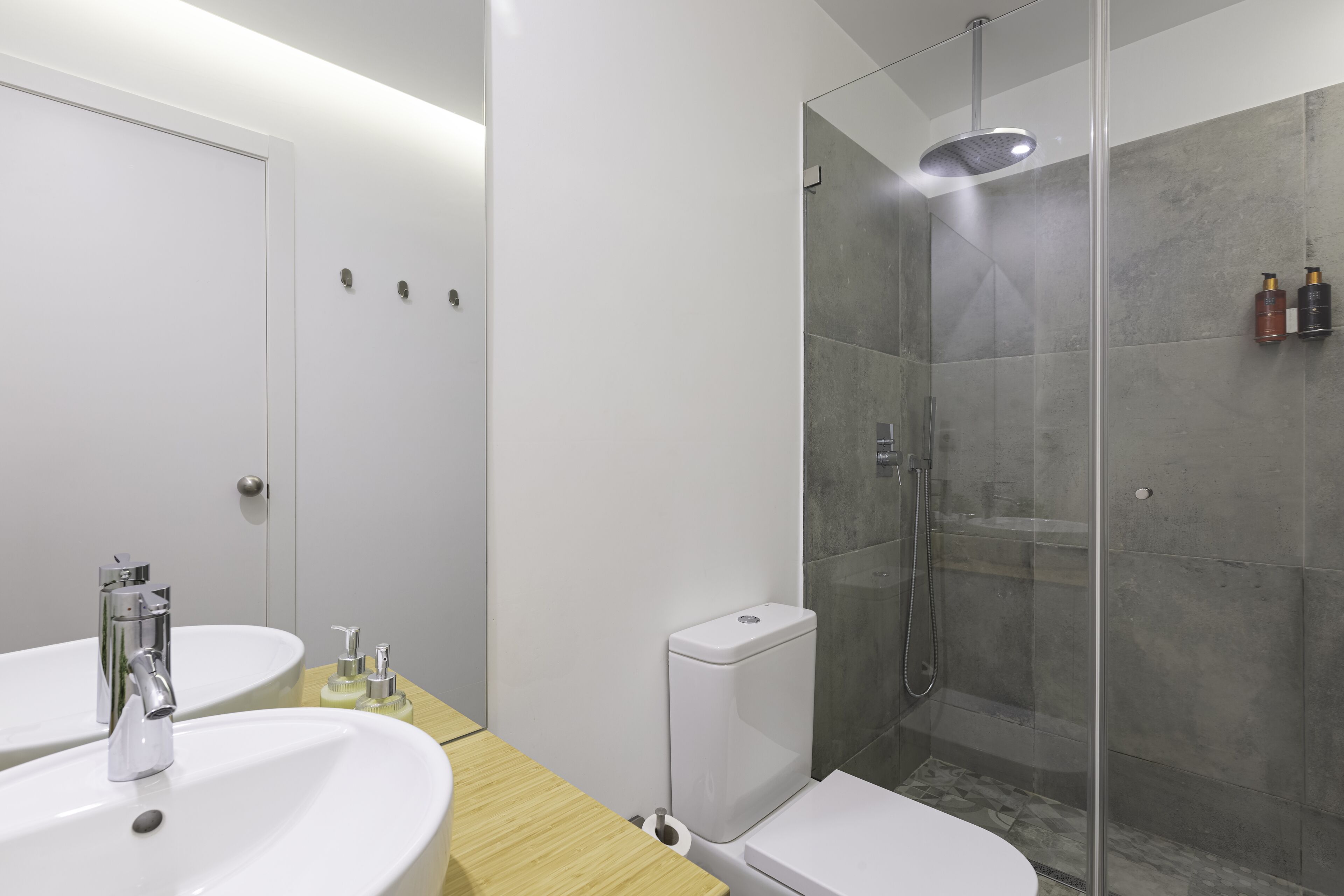 Un bagno moderno con doccia vetrata, due lavandini e il water.