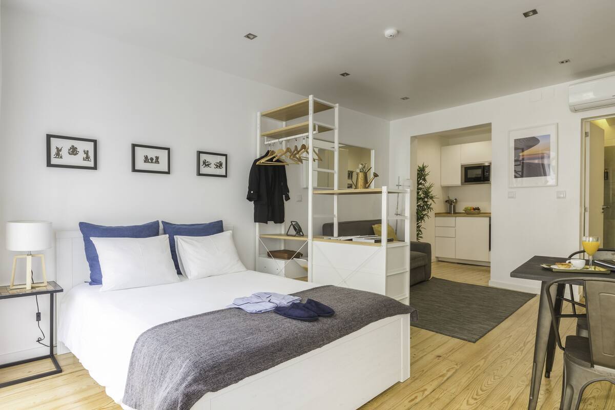 A modern bedroom with a bed, bedside table, and a built-in desk with a chair.