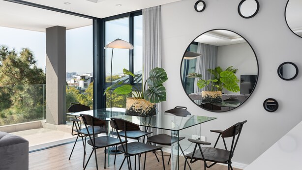 A modern dining area with a glass table and chairs, large windows, and potted plants. - Warwick 401 - Adults Only (Cape Town)