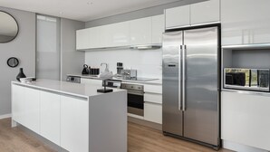 A modern kitchen with white cabinetry, a stainless steel refrigerator, and a central island. - Warwick 401 - Adults Only (Cape Town)