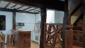 Une cuisine rustique avec des poutres apparentes, un escalier en bois et un sol carrelé.