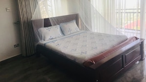 A bedroom with a bed, curtains, and a mosquito net.