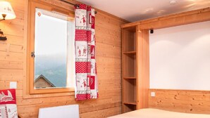 Una stanza accogliente in legno con un letto, una finestra vista e un termosifone.