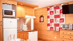 Una cucina compatta con mobili in legno, un forno a microonde, una macchina per il caffè e un piccolo frigorifero.