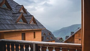 Un edificio in legno con tetto spiovente, un balcone con ringhiera in legno e montagne sullo sfondo.