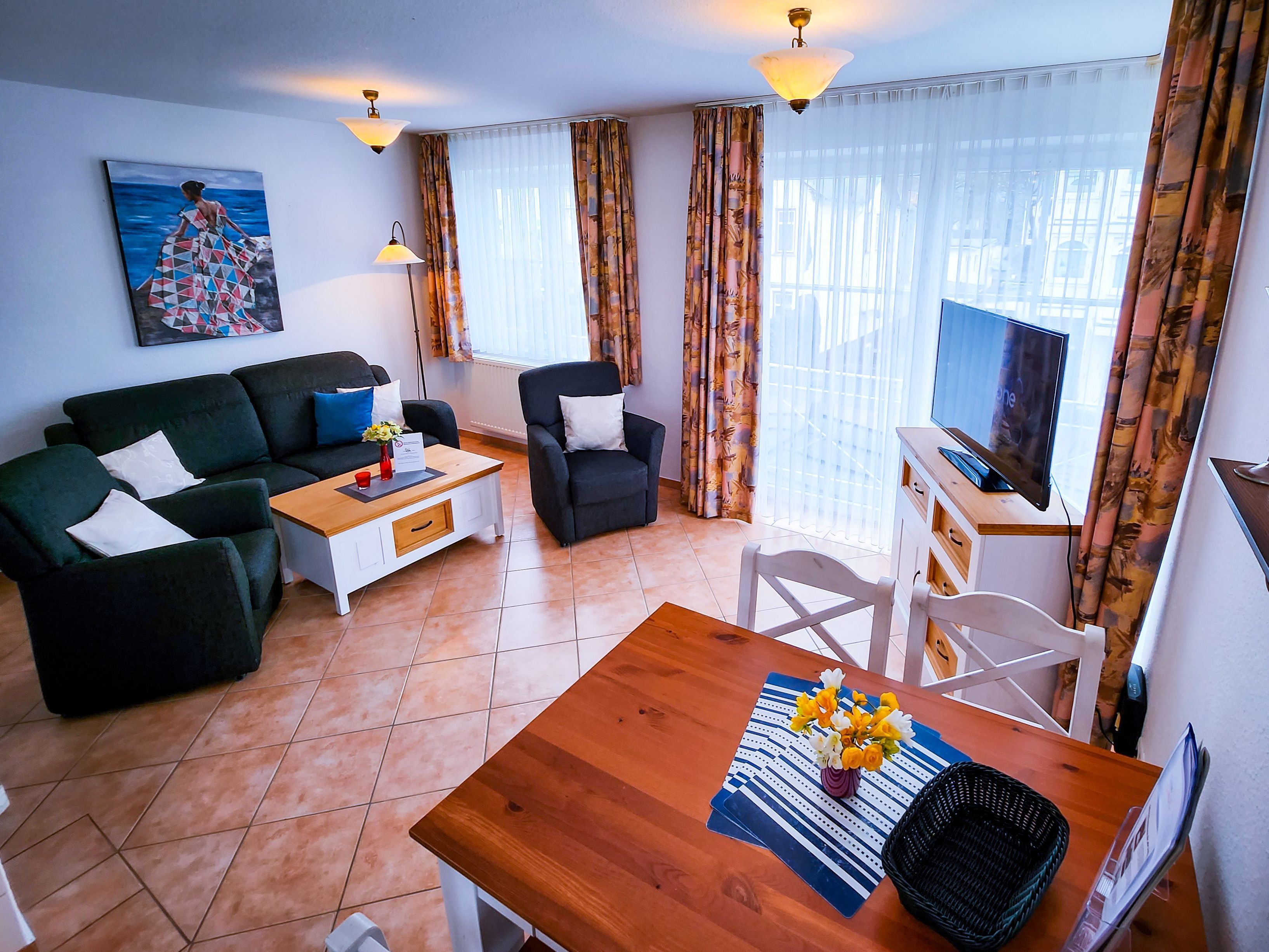 A living room with a sofa, armchair, coffee table, TV, and a painting on the wall.