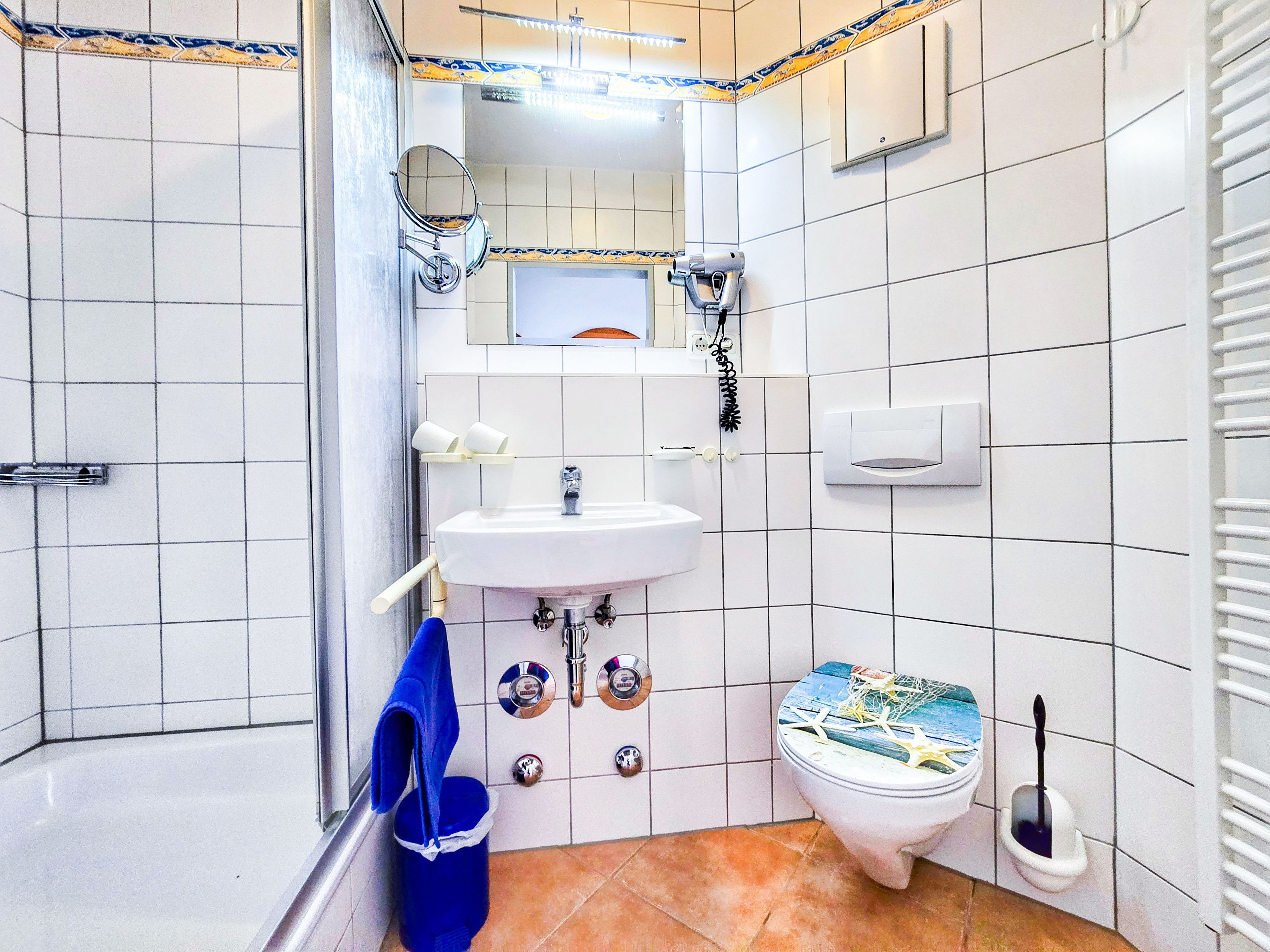 Ein Badezimmer mit Waschbecken, Spiegel, Toilette und einem blauen Handtuch an der Wand.
