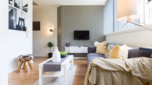 Un salon moderne avec un canapé gris, une table basse blanche et un téléviseur fixé au mur.