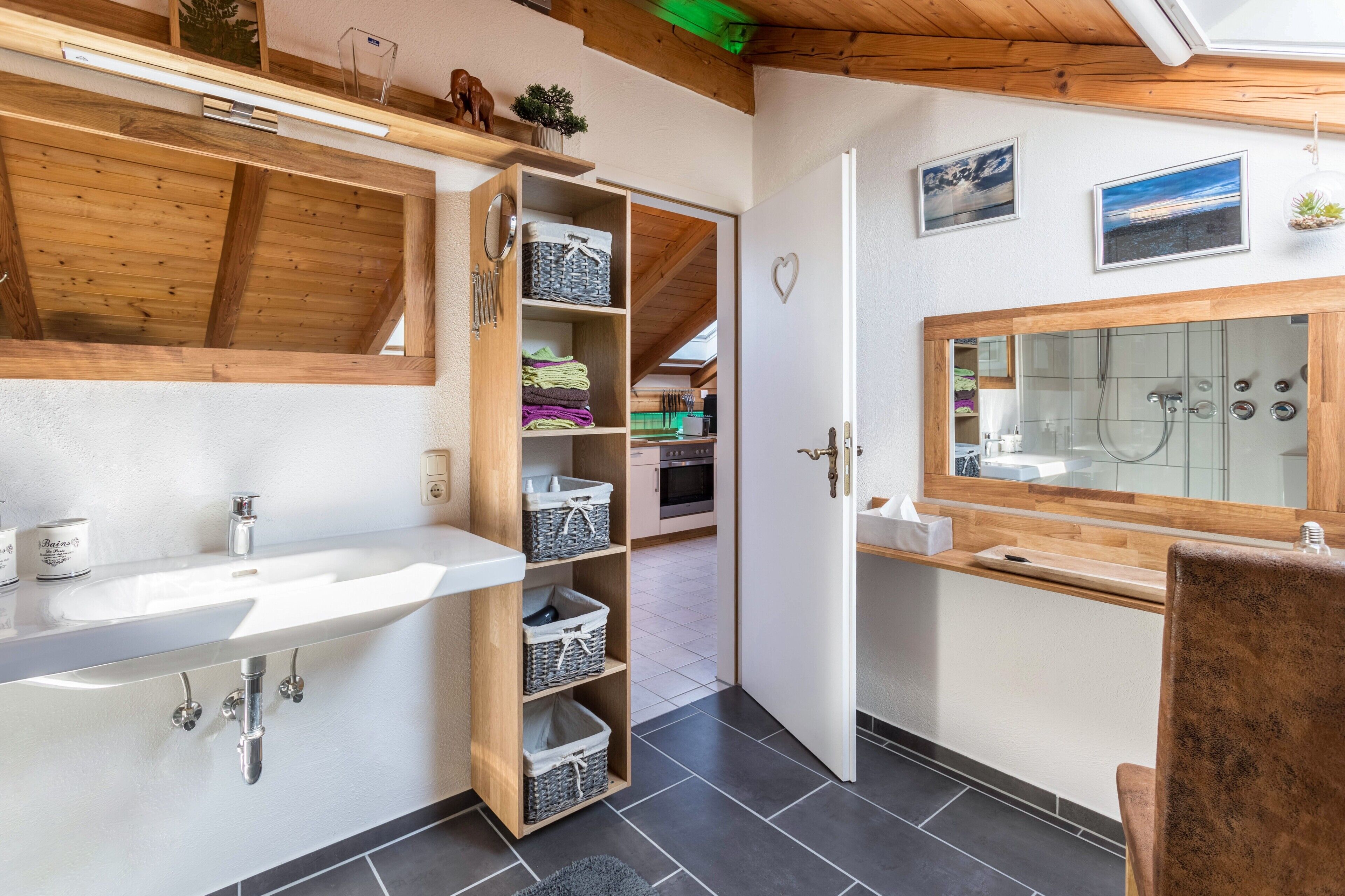 Un baño con un lavamanos grande, estantes de madera, un espejo y una zona de ducha.