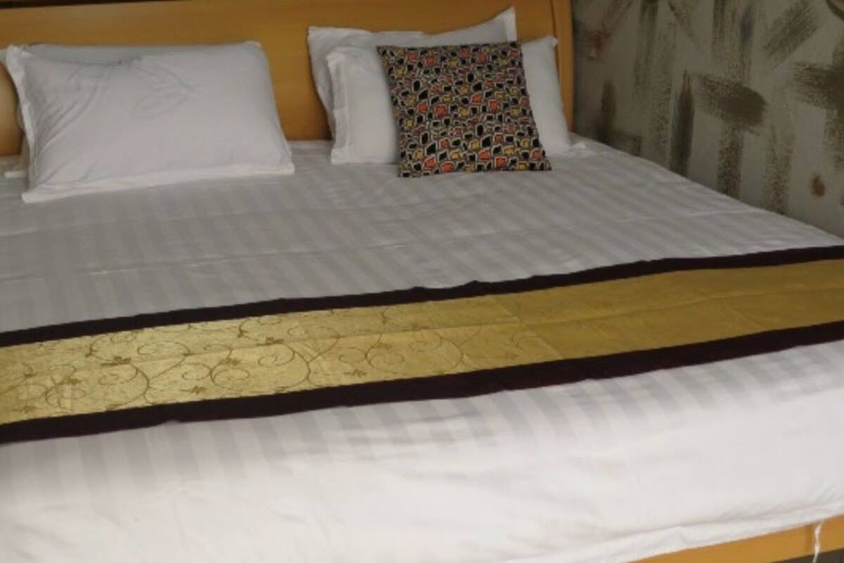 A bed with white bedding and a decorative gold and black bedspread.