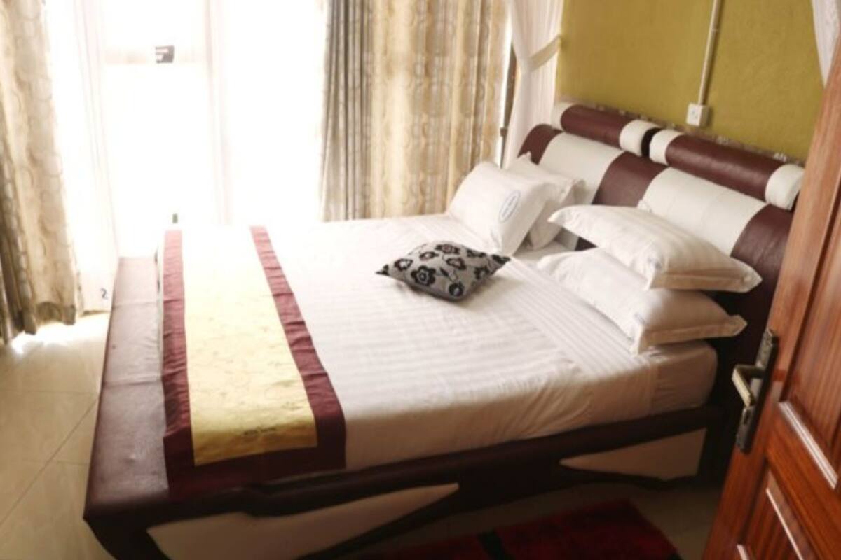A bed with a wooden frame, white bedding, and a patterned pillow.