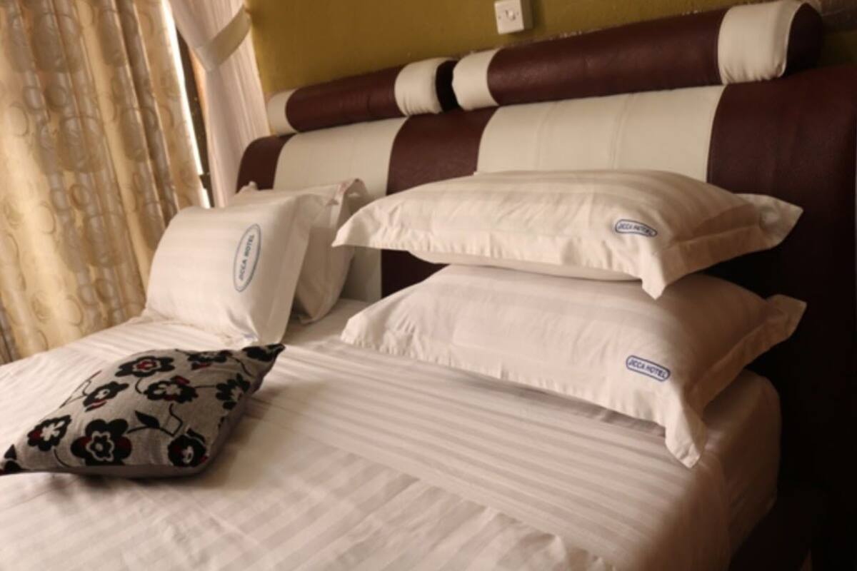 A bed with white bedding and decorative pillows, a brown headboard, and a floral-patterned pillow.