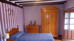 Une chambre avec deux lits, une armoire en bois, une commode et une fenêtre avec des rideaux.