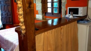 Una cocina con mostrador de madera, microondas y pared de piedra.
