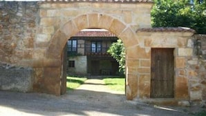 Ein steiner Torbogen führt zu einem Gebäude mit einem Ziegeldach.