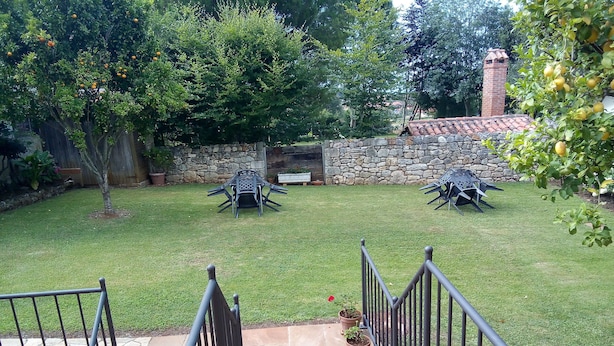 Ein Garten mit Steinmauer, Backsteinofen und einer Terrasse mit Gartenmöbeln.