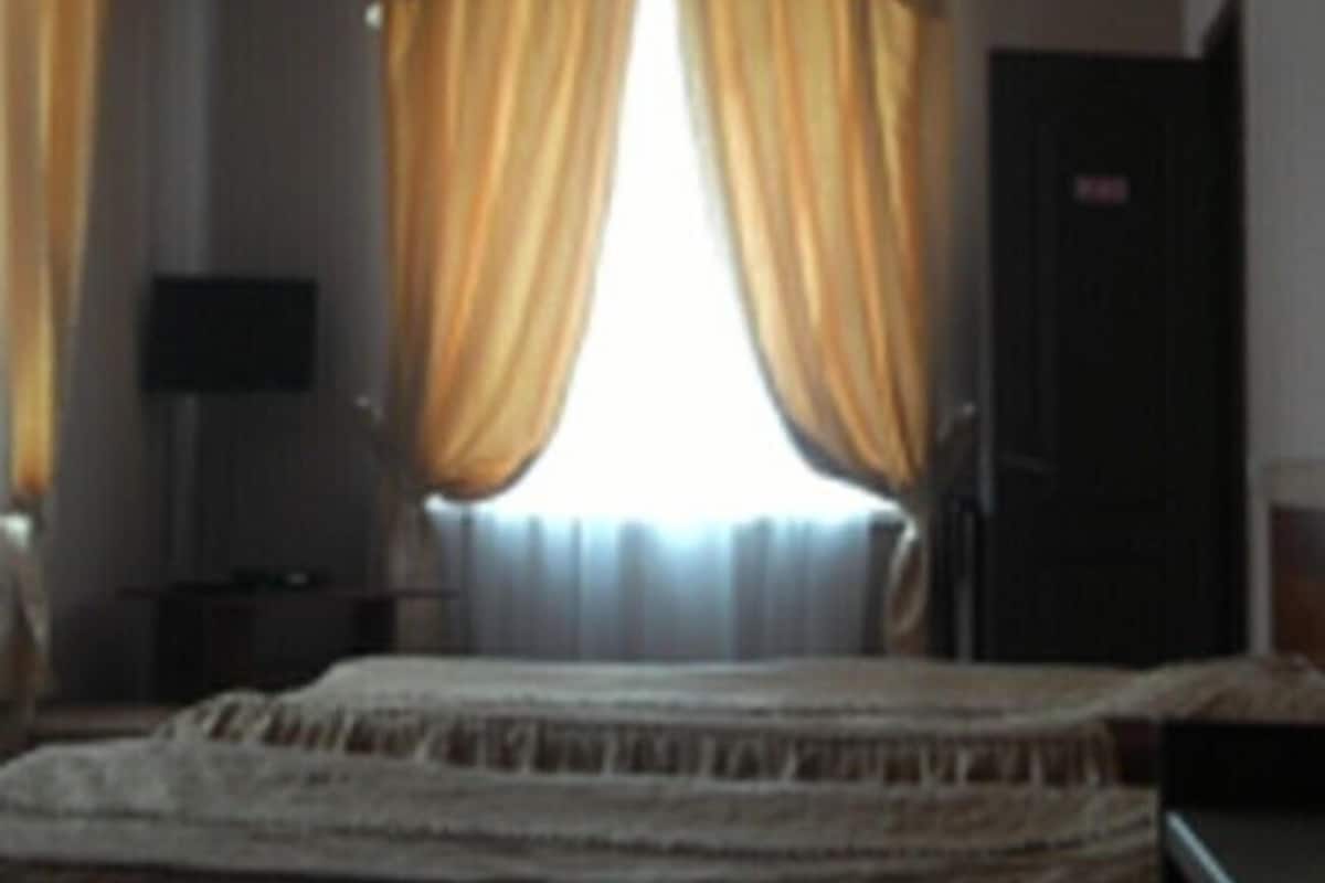 A hotel room with a bed, curtains, a television, and a door.