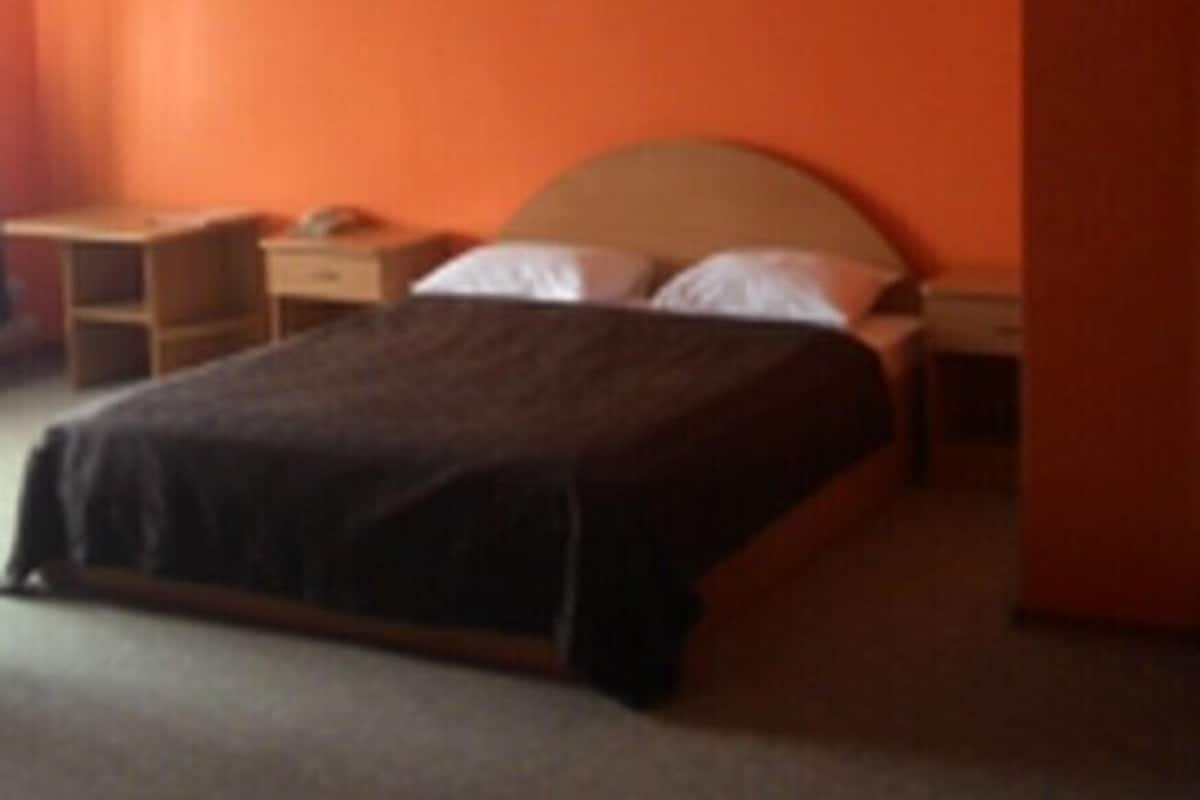 A bedroom with a bed, nightstand, and a desk.