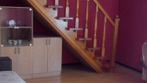 A room with a wooden staircase, a dining table, and a sofa. - Galant Hotel (Boryspil)