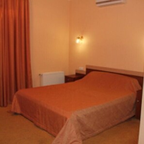 Ein Hotelzimmer mit Bett, Nachttisch, Klimaanlage und Wandleuchte.