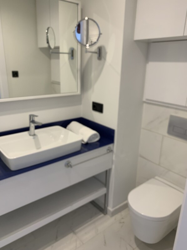 A modern bathroom with a white sink, a mirror, and a toilet.