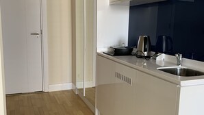 A modern kitchen with white cabinetry, a wooden floor, and a built-in oven. - Orbi city Davide (Batumi)