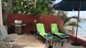 Un patio con dos sillones de descanso, una parrilla y una botella de champán.