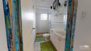 Baño con inodoro, lavamanos y ducha. Cuenta con una ventana que proporciona luz natural.