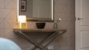 Un meuble-lavabo de salle de bain avec un miroir, un récipient, un vase avec des fleurs et une lampe.