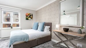 Une chambre à coucher moderne avec un lit, une table de chevet, un miroir et une fenêtre.