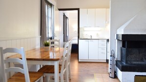 Una cocina compacta con armarios blancos, una mesa de comedor de madera y sillas.