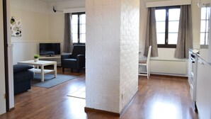 Una sala de estar moderna con un televisor de pantalla plana, un sofá, una mesa de centro y un separador de ladrillo blanco.