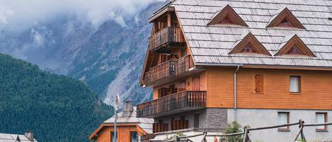Eine Holzhütte mit Balkon vor einer Bergkulisse.