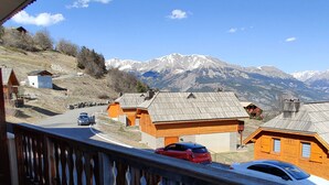 A mountain view with wooden cabins, a road with cars, and a clear sky. - 3-room apartment, sleeps 8, balcony, parking (Uvernet-Fours)