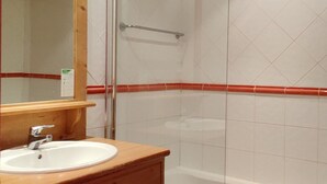 A bathroom with a wooden vanity, a white sink, a mirror, and a glass shower enclosure. - 3-room apartment, sleeps 8, balcony, parking (Uvernet-Fours)