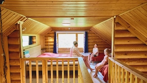 A cabin with a loft bedroom, a wooden staircase, and a large window. - Serena Villas (Espoo)