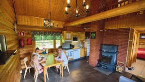 A wooden interior with a dining area, kitchen, and fireplace. - Serena Villas (Espoo)