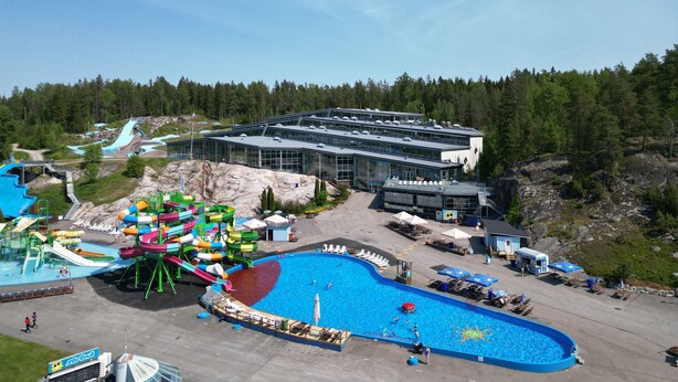 A water park with a large pool, slides, and a building with multiple levels. - Serena Villas (Espoo)