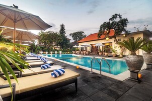Un área junto a la piscina con sillones, sombrillas y una pileta.