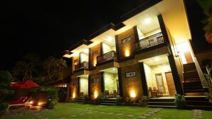 A multi-story hotel with a well-lit exterior, a covered outdoor seating area, and a staircase leading to the entrance. - Hotel Segara Agung (Denpasar)